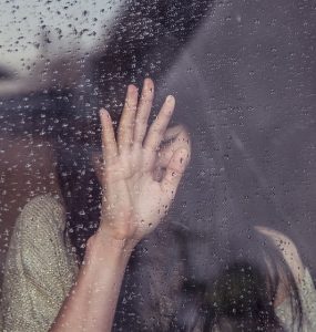 girl with hand pressed to window